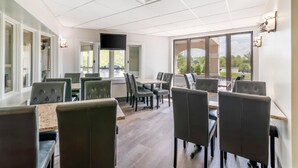 A modern dining area with multiple tables and chairs, large windows, and a flat-screen TV mounted on the wall. - Black Bear Inn, an Ascend Collection Hotel (Orono)