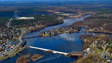 An aerial view of a town with a dam, a river, and surrounding forests.