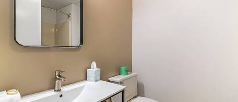 Ein Badezimmer mit Waschbecken, Spiegel, Toilette und einer beige gestrichenen Wand.