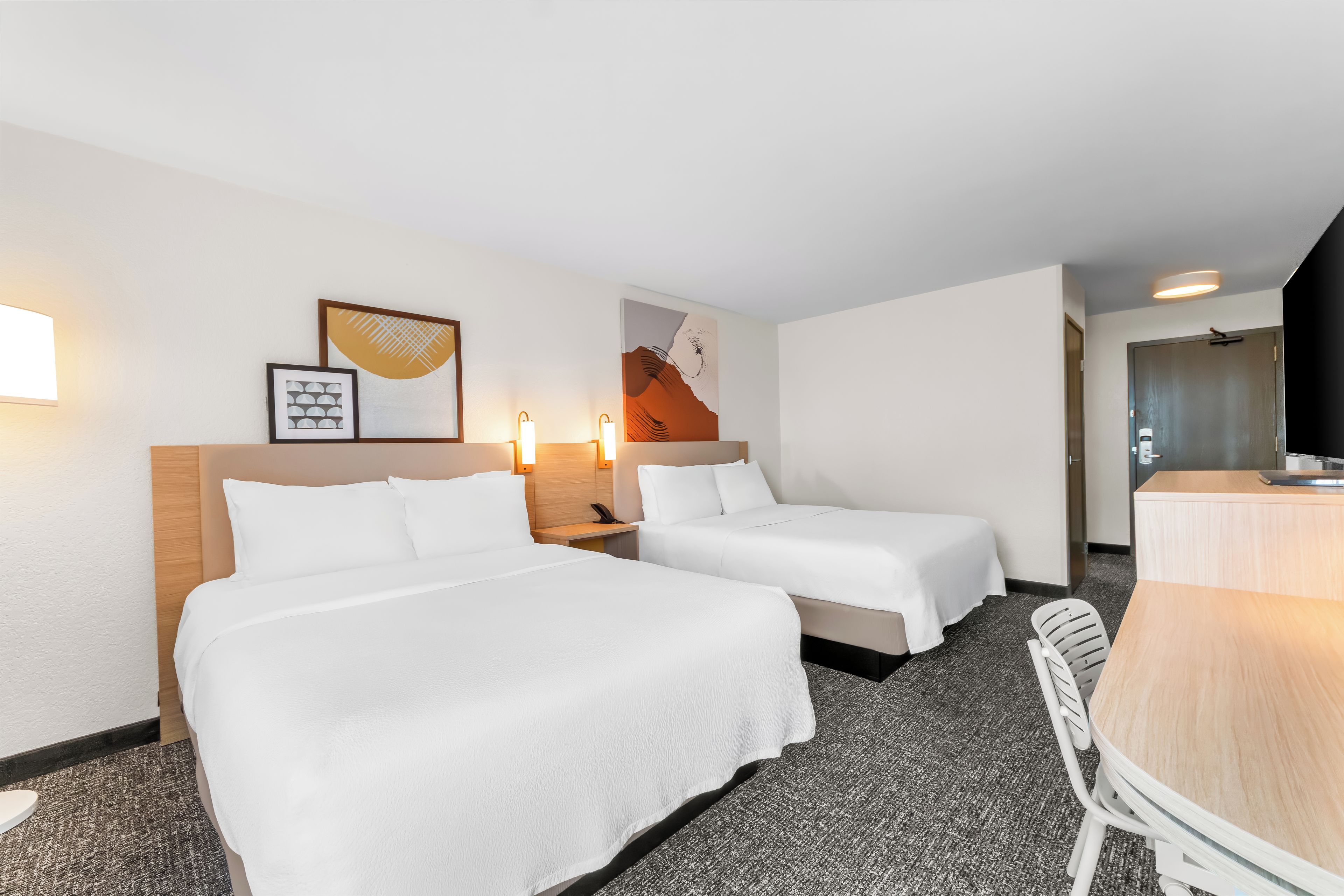 Een hotelkamer met twee bedden, een bureau en een stoel.