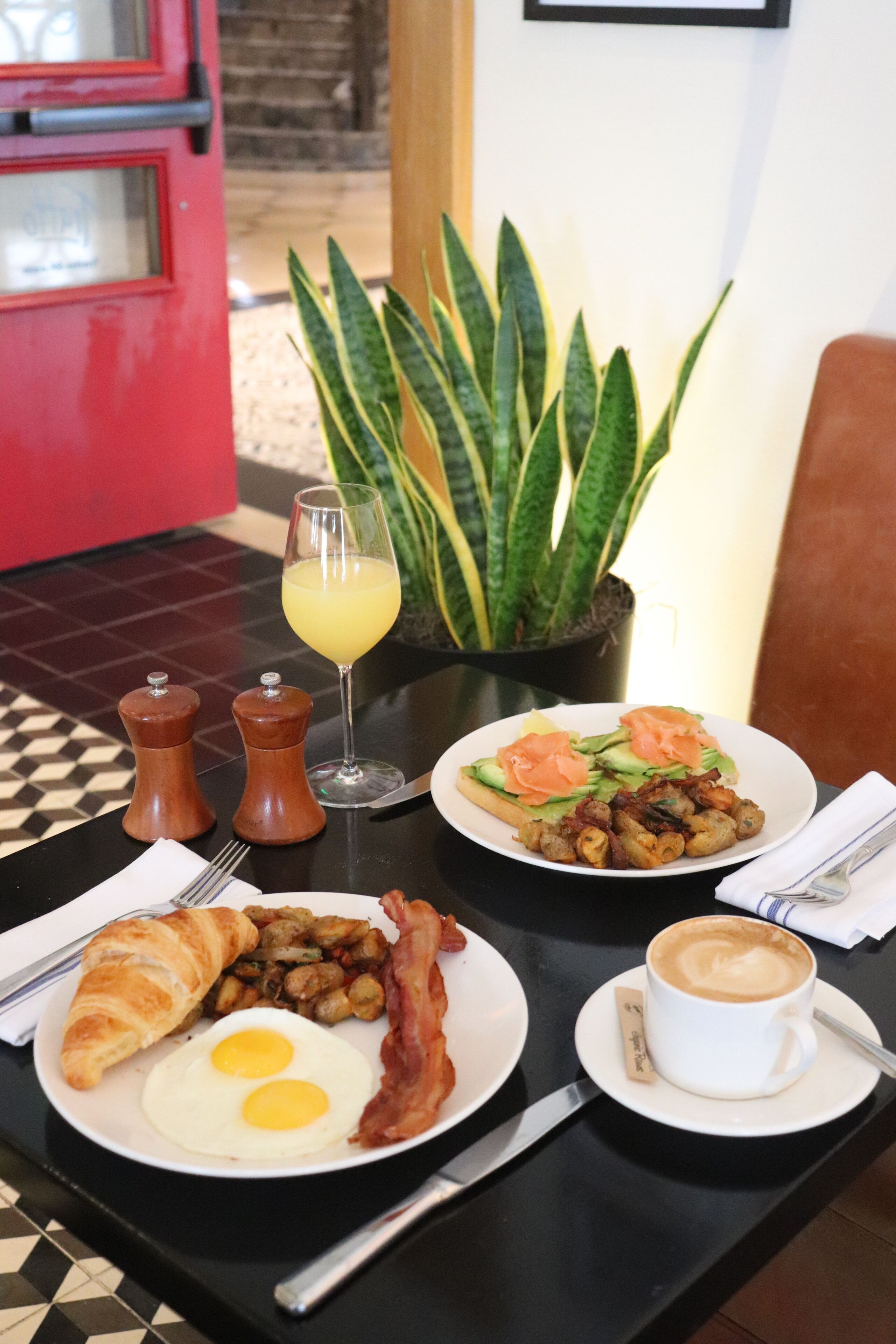 Une table de petit-déjeuner avec des assiettes d’œufs, de bacon, de pain grillé et du café.