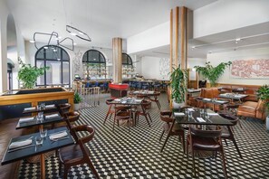 Ravintolassa on ruutukuviollinen lattia, puupöydät, nahkaiset tuolit ja suuret ikkunat.