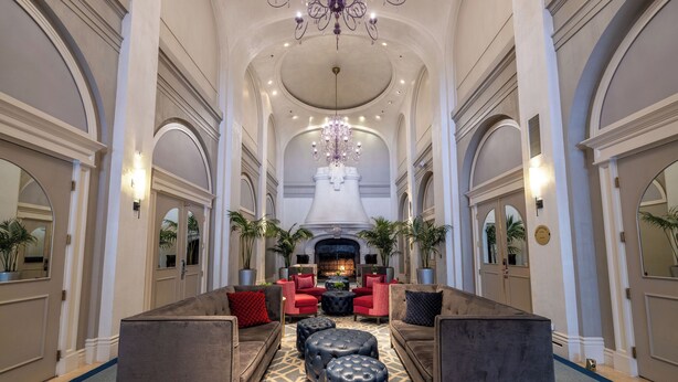 Un lobby espacioso con techos altos, candelabros y una chimenea.