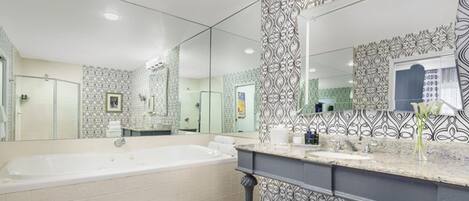 A modern bathroom with a large bathtub, a vanity with a mirror, and patterned tiles.