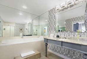 Un baño moderno con una bañera grande, un tocador con espejo y baldosas estampadas.
