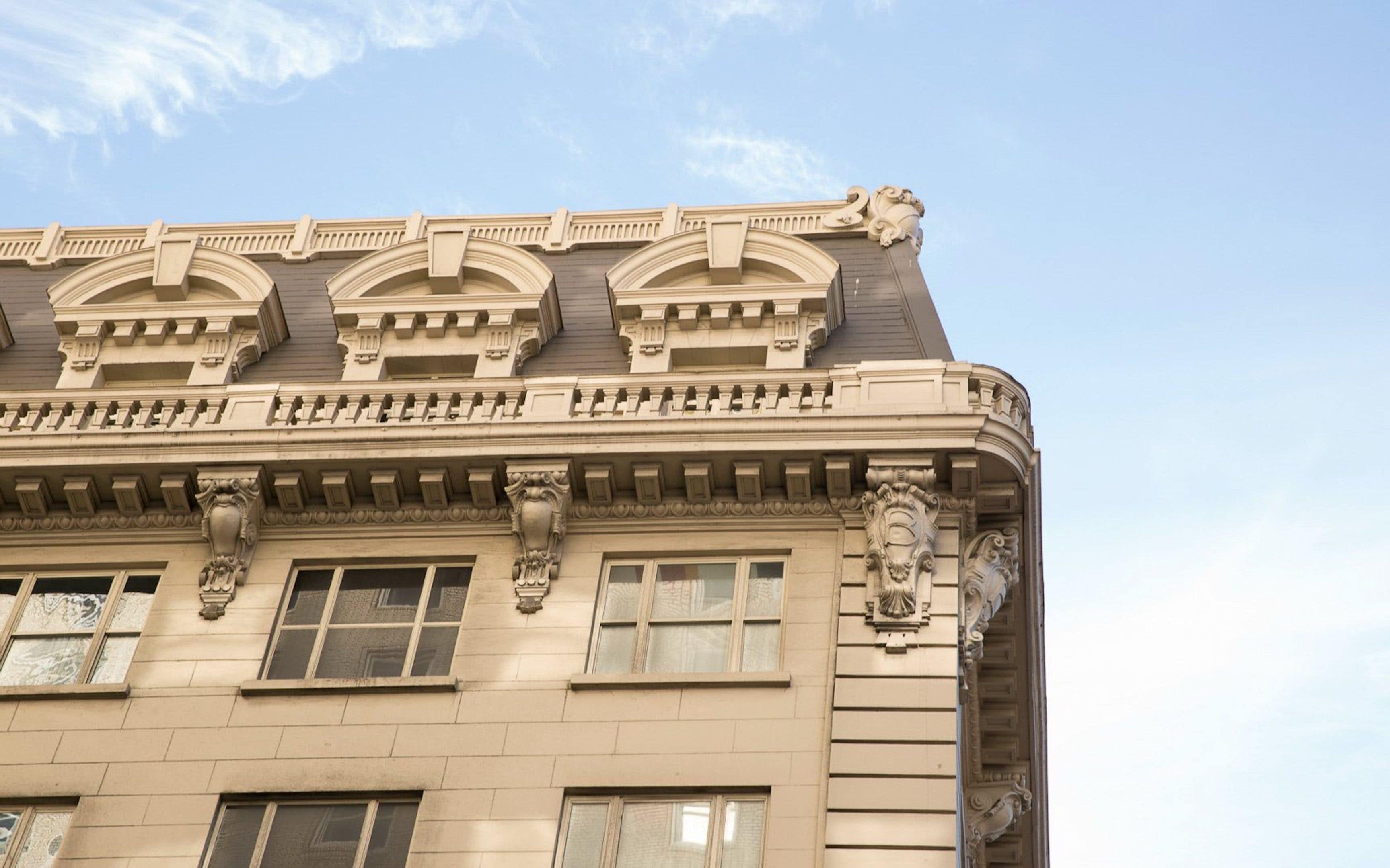 A building with ornate architectural details, including decorative moldings and a lion statue on the roof.