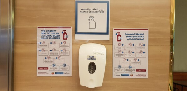 A hand sanitizer dispenser with instructions in multiple languages. - Treffen House Doha - Souq Waqif and next to Msheireb Metro Station (Doha)