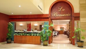Un vestíbulo de hotel con una recepción, plantas en macetas y un letrero que dice 'La Brasserie'.