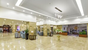 Un moderno vestíbulo de hotel con mostrador de recepción, zona de estar y una vitrina de cristal.