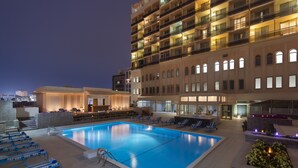 Un área de piscina hotelera con sillas de descanso y una piscina grande.