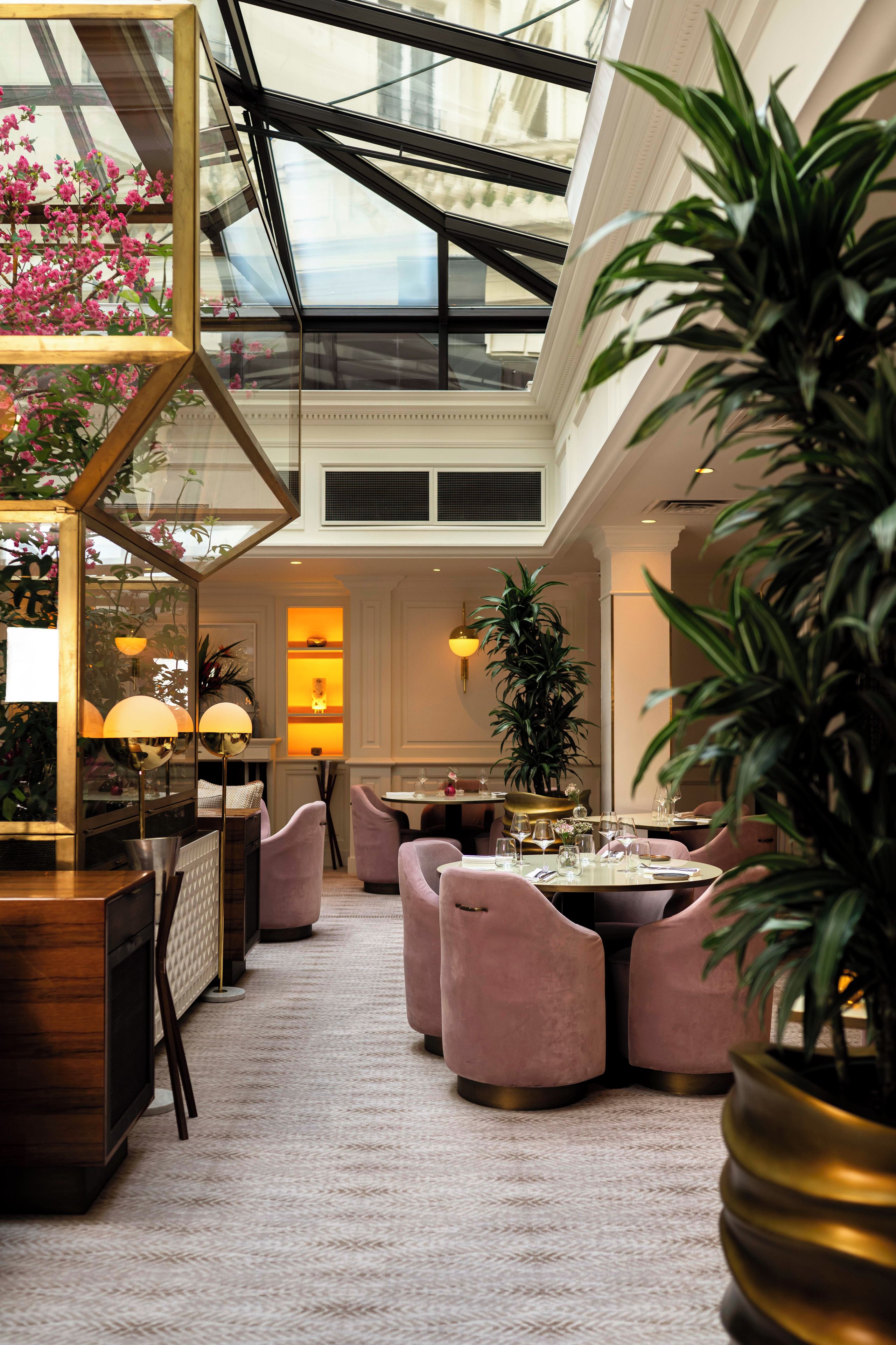 Un hall d’hôtel doté d’un plafond haut, d’un atrium en verre et d’un espace salon avec des fauteuils confortables.