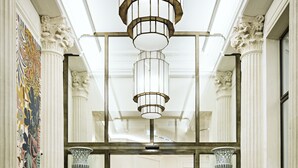 Un lobby imponente con piso a cuadros, columnas ornamentales y una araña de cristal.