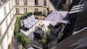 A rooftop terrace with a dining table, chairs, and an umbrella.
