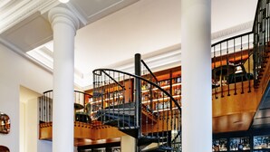A spacious lobby with a central bar area, multiple seating options, and a prominent spiral staircase.