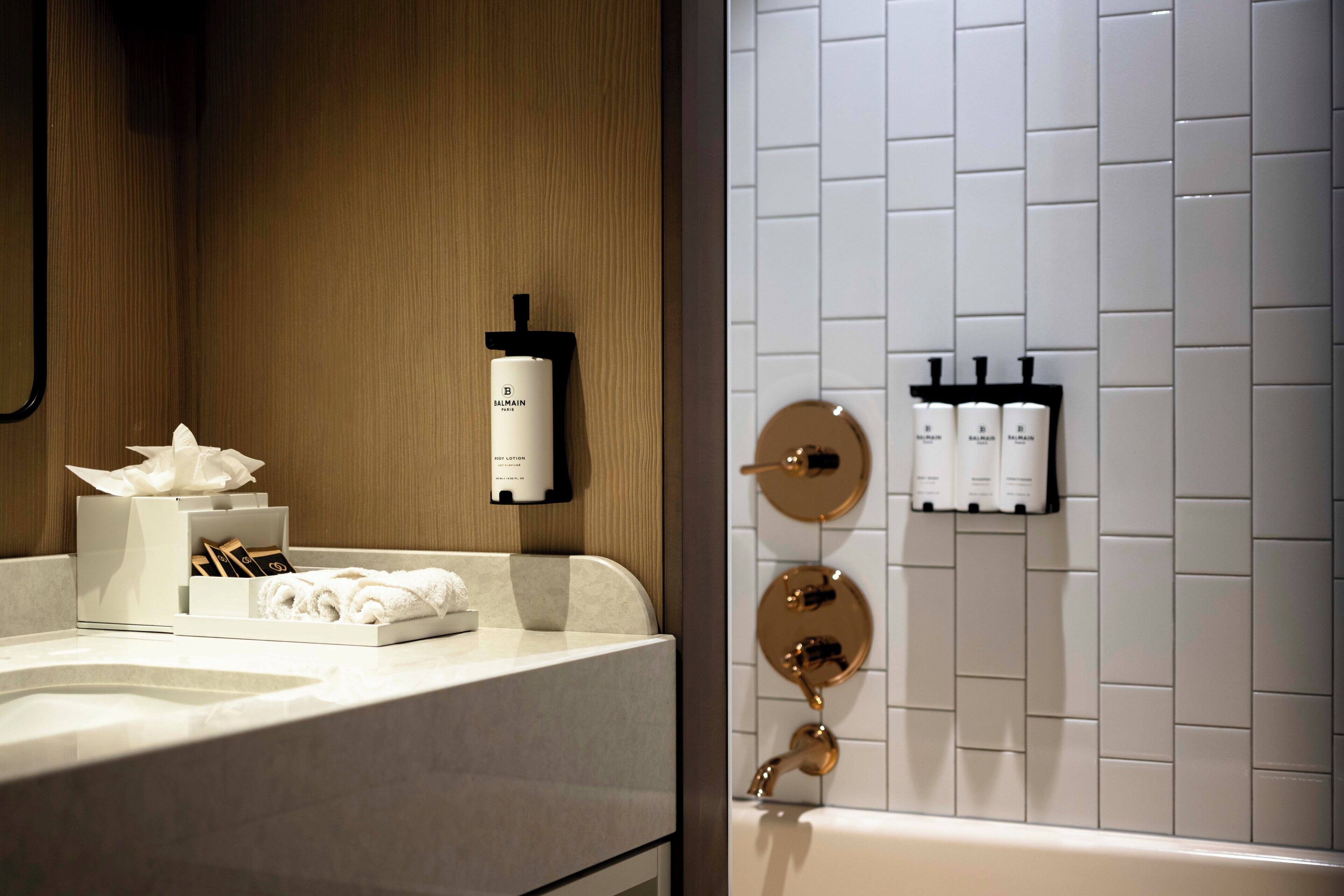 A bathroom with a marble sink, a tissue box, a bottle of shampoo, and a towel rack.