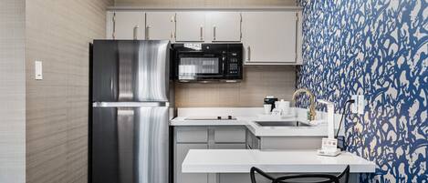 A modern kitchen with stainless steel appliances, a white countertop, and a patterned wall.