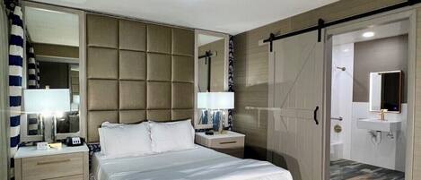 A modern bedroom with a large bed, a bedside table, a mirror, and a wardrobe.