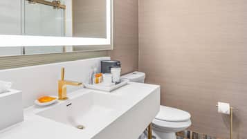 A modern bathroom with a white vanity, a large mirror, a toilet, and a patterned floor.