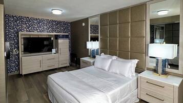 A modern hotel room with a large bed, a TV, a wardrobe, and a mirror.