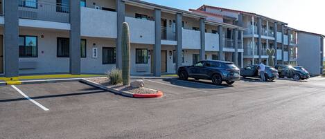 A multi-story hotel with a parking lot, several cars, and a cactus in the foreground.