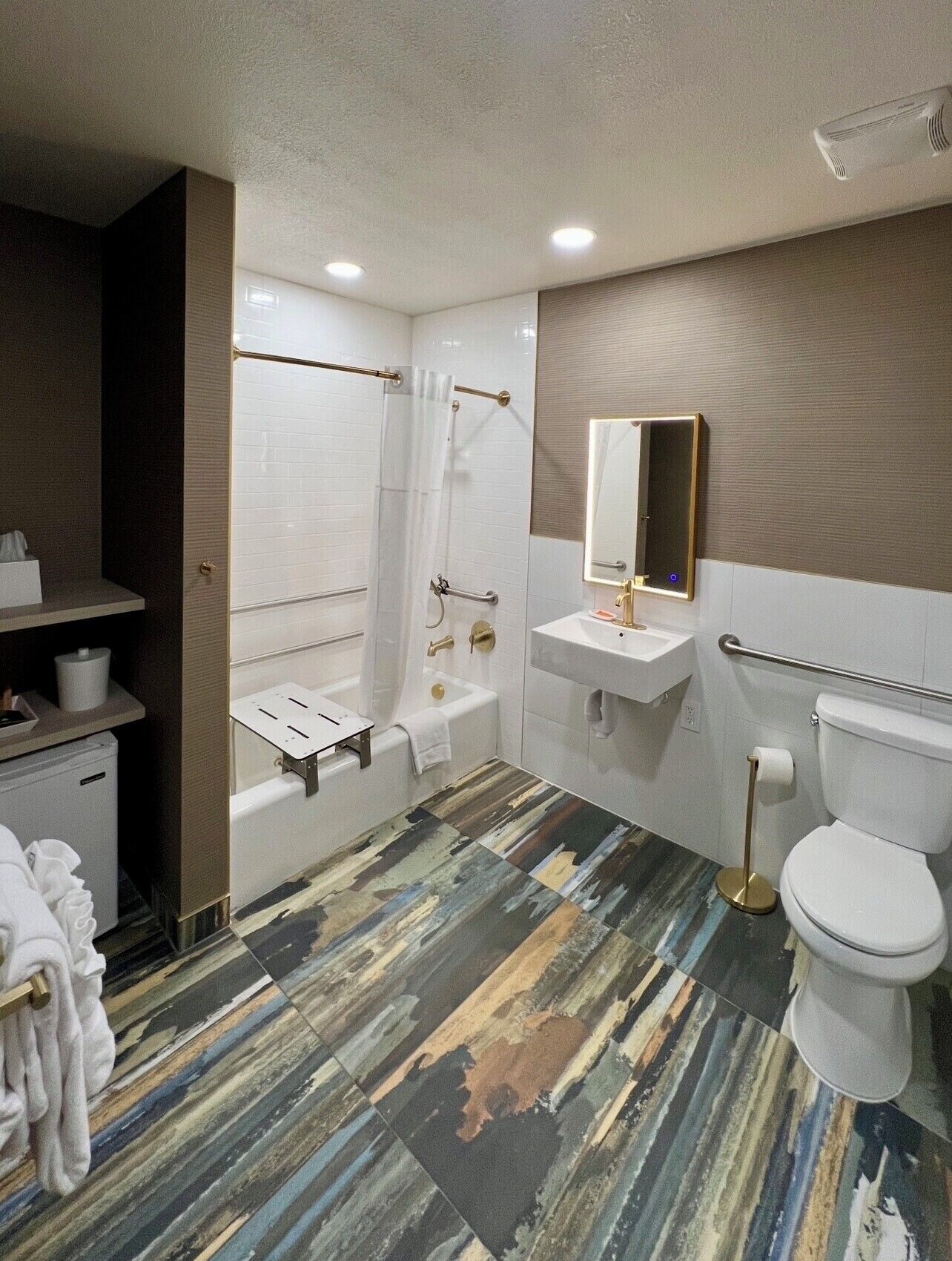 A bathroom with a bathtub, a sink, a toilet, and a mirror.