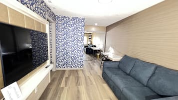 A modern living room with a flat-screen TV, a grey sofa, and a patterned partition.