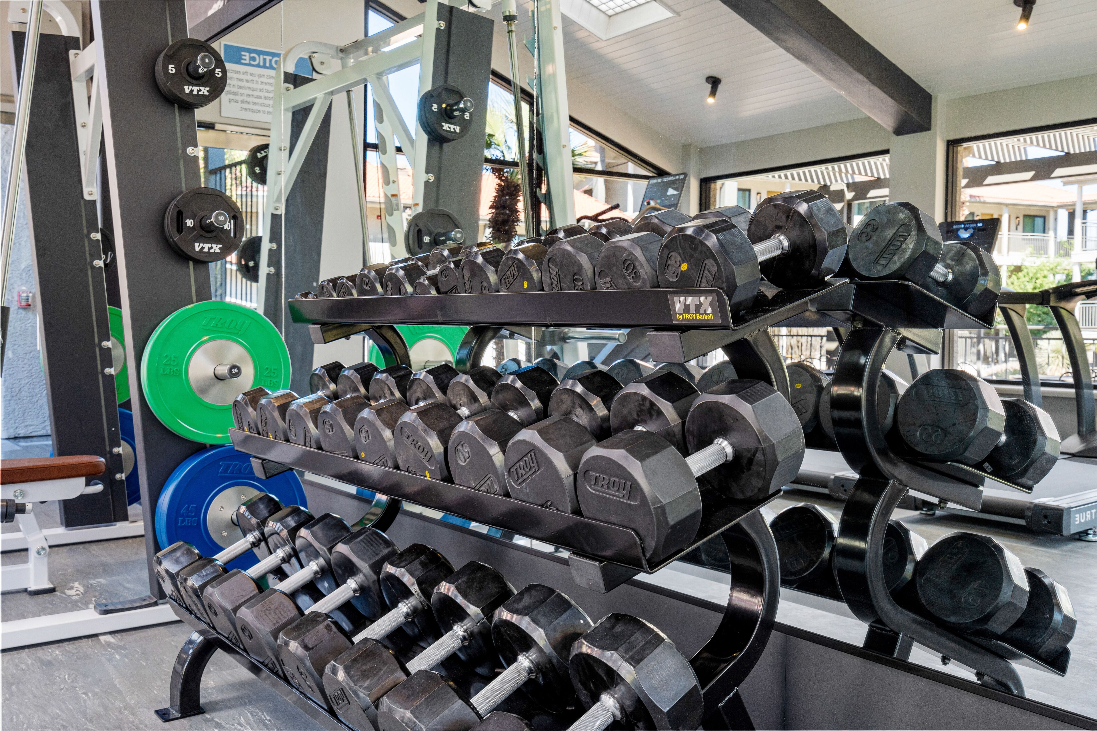 A gym with various weightlifting equipment, including dumbbells and weight plates.