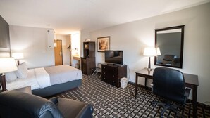 A hotel room with a bed, a desk, a chair, a TV, and a mirror. - Quality Inn & Suites Watertown near Prairie Lakes Ice Arena (Watertown)