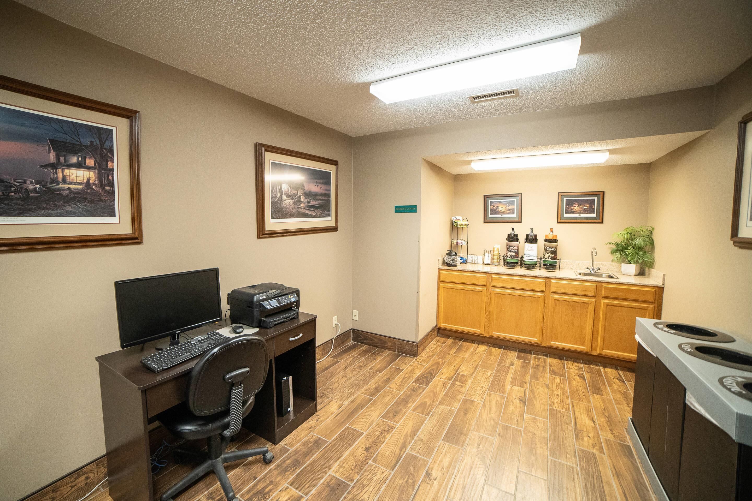 A hotel room with a desk, computer, and a bar area with bottles.