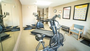 A fitness room with exercise equipment, a mirror, and informational posters on the wall. - Quality Inn & Suites Watertown near Prairie Lakes Ice Arena (Watertown)
