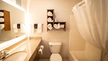 A bathroom with a sink, toilet, and shower. There is a towel rack with towels and a shelf with additional towels.