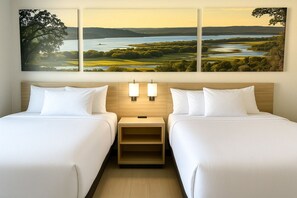 A hotel room with two beds, a nightstand with lamps, and a large landscape painting above the beds.