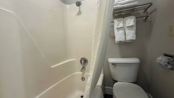 A bathroom with a bathtub, toilet, and a towel rack with folded towels.