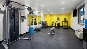 Un gimnasio con equipo de ejercicio, una banca, una cinta de correr y una bicicleta estática.