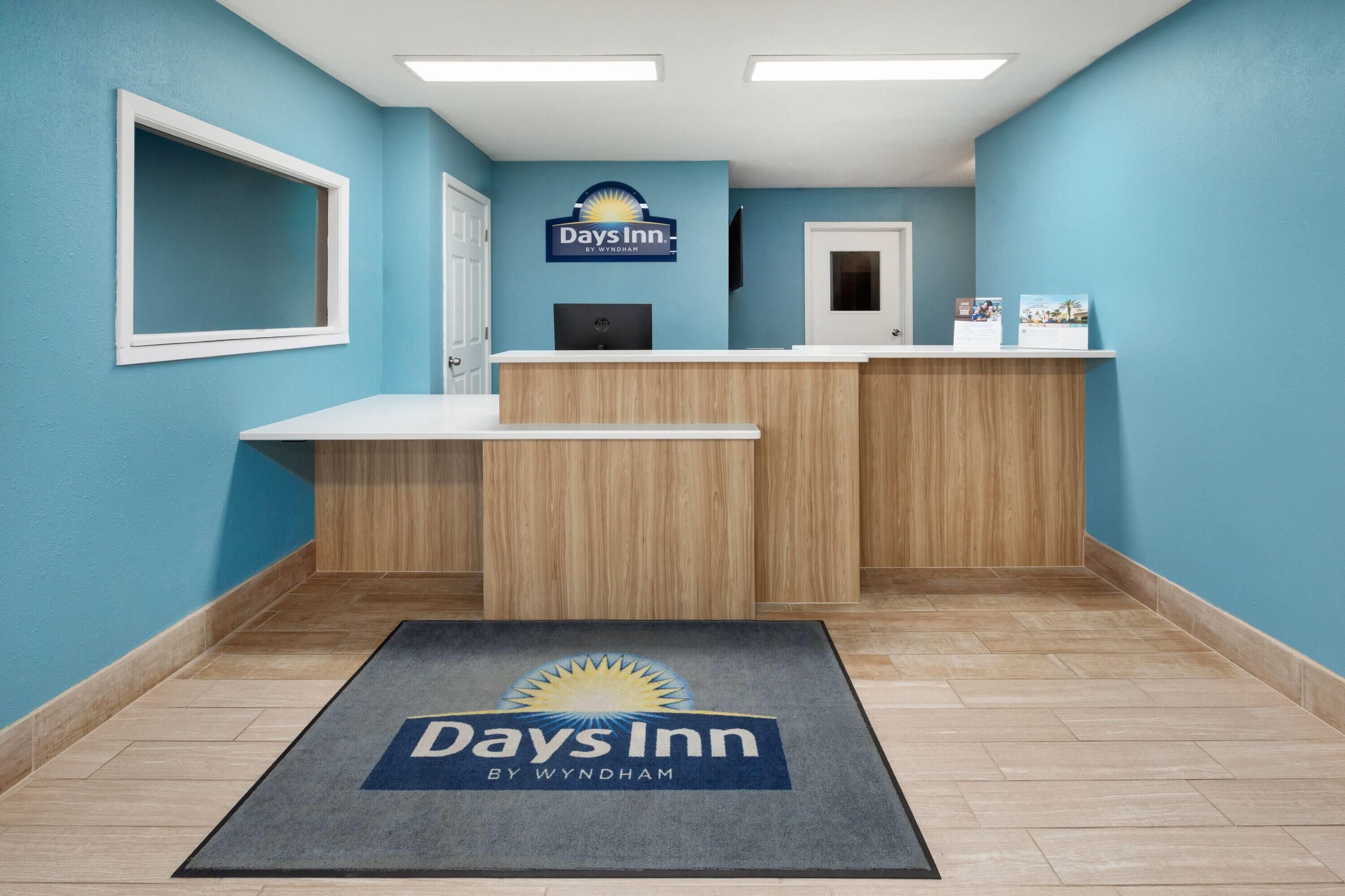 A reception area with a blue wall, a reception desk, a computer, and a door.