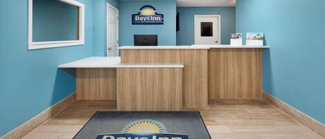 A reception area with a blue wall, a reception desk, a computer, and a door.
