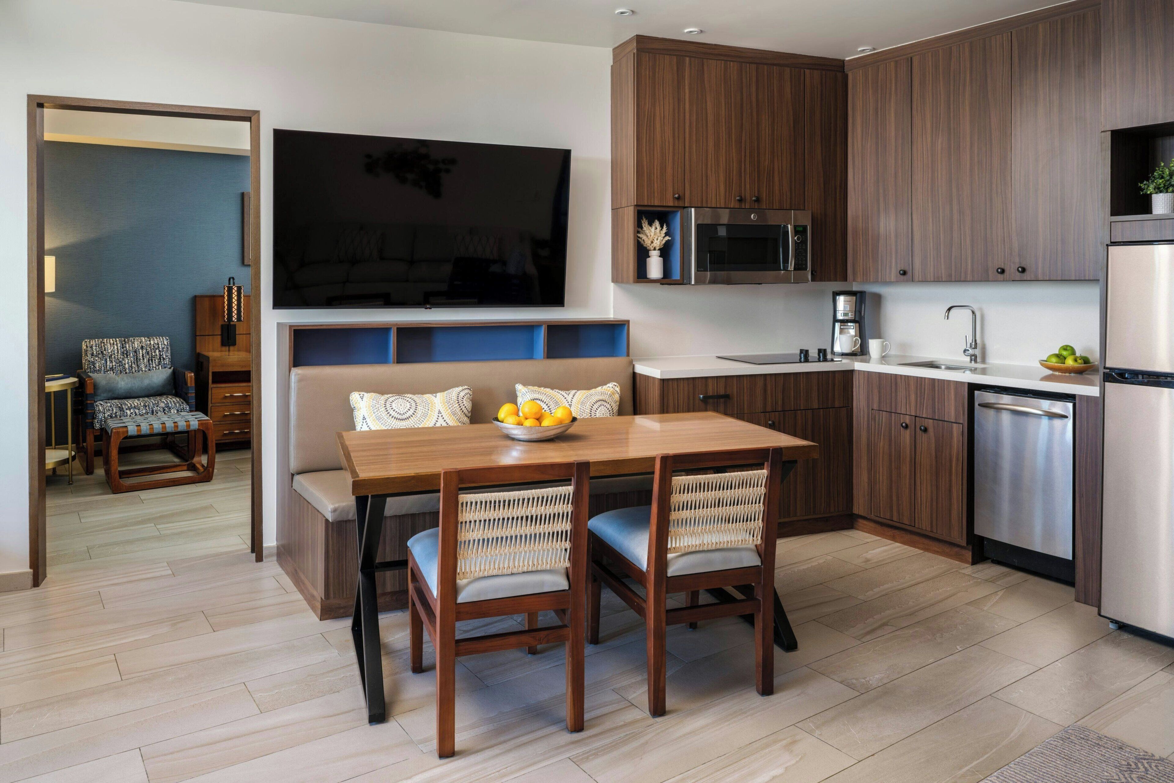 A modern kitchen with wooden cabinets, a built-in microwave, and a stainless steel refrigerator.