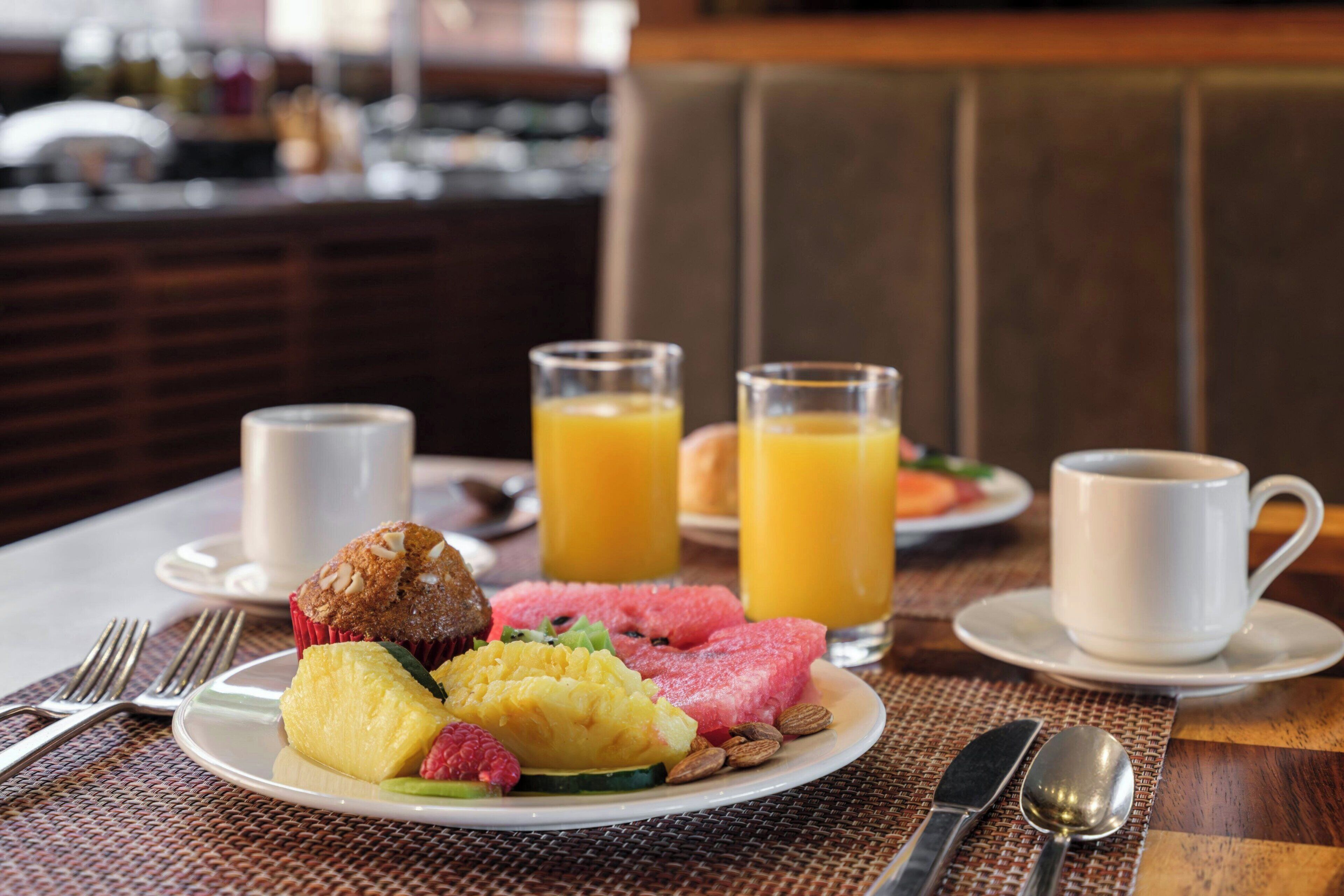 Ein Frühstückstisch mit einem Teller Essen, zwei Orangensaftgläsern und einer Kaffeetasse.