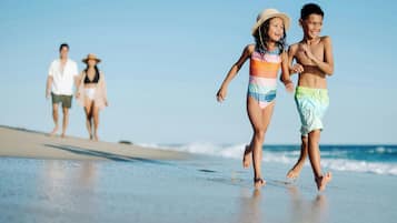 Escena de playa con una familia caminando por la orilla.