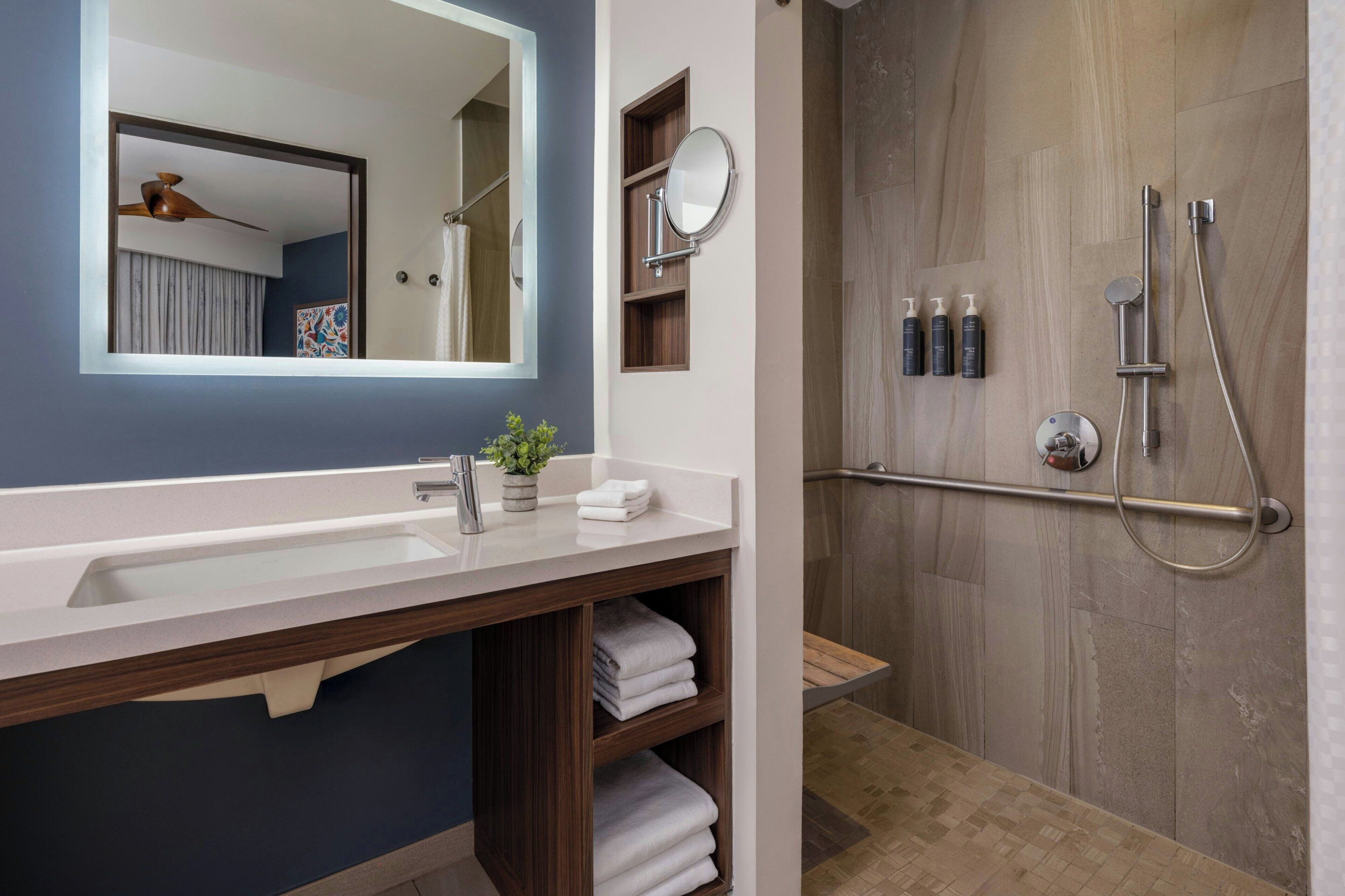 Une salle de bain moderne avec un meuble-lavabo, une douche et un miroir.