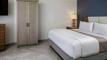 A hotel room with a bed, a wardrobe, a nightstand with a lamp, and a television on the wall.