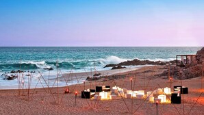 A beach setting with a row of white and black square structures, possibly seating or tables, arranged on the sand. - The Westin Los Cabos Resort Villas (San José del Cabo)