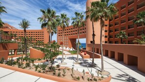 A hotel with a modern architectural design, featuring a central courtyard with palm trees and a pool. - The Westin Los Cabos Resort Villas (San José del Cabo)