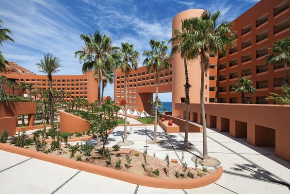 Un hotel de diseño arquitectónico moderno, con un patio central con palmeras y una piscina.