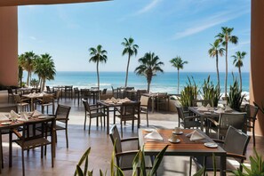 Un restaurante frente al mar con mesas y sillas dispuestas para comer, con vista al océano.