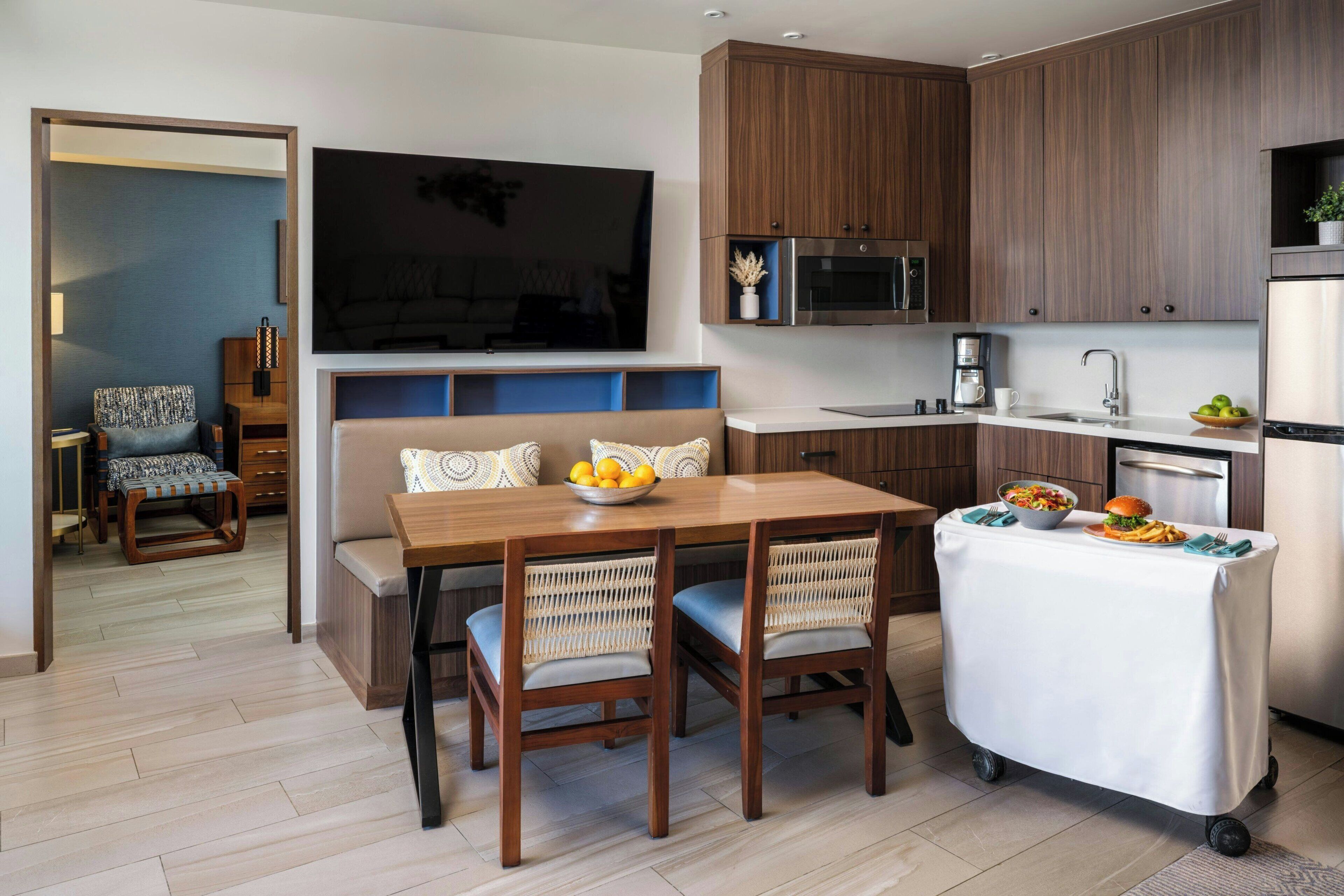 A modern kitchen with wooden cabinets, a built-in microwave, and a stainless steel refrigerator.