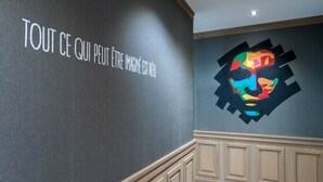 Una pared con una cita en francés y una obra de arte abstracta y colorida.
