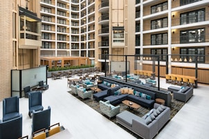 A spacious indoor lobby with multiple seating areas, including sofas and chairs, and a central coffee table.