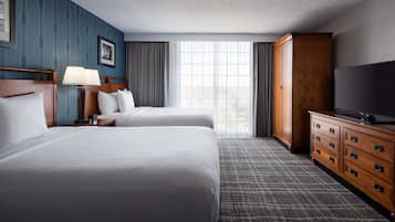 Une chambre d’hôtel avec deux lits, une commode, un téléviseur et une grande fenêtre.