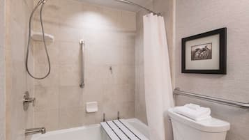 A bathroom with a shower, toilet, and a framed picture on the wall.